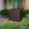 A dark brown storage box is placed on a patio next to plants and greenery. Podgląd zdjęcia produktu