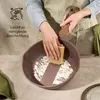 A person is cleaning a frying pan with a sponge, demonstrating its easy-to-clean coating. Voir les images du produit