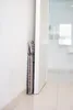 A folded stool is leaning against a white wall next to a doorway. Produktbild-Vorschau