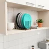 A kitchen shelf with a plate rack holding several plates, bowls, and a small potted plant. Náhled obrázku produktu