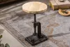 A close-up shot of an industrial-style adjustable stool on a patterned rug, with a book and a small bowl of items in the background. Produktbild-Vorschau