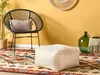 A cozy living room corner with a chair, pouf, rug, and decorative items. Náhľad obrázku produktu