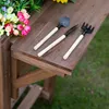 Gardening tools and artificial flowers on a wooden table. Produktbild-Vorschau