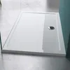A white rectangular shower tray with a silver drain is shown on a concrete floor. Produktbild-Vorschau