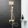 A gold shower system with a rainfall showerhead and handheld showerhead is shown against a dark gray tiled wall and a white wall. Produktbild-Vorschau