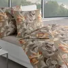 A bed with bedding and pillows in a room with a large window overlooking trees. Produktbild-Vorschau