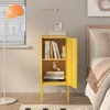 A yellow metal cabinet with books and decorative items, placed next to a bed in a bedroom. Podgląd zdjęcia produktu