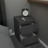 A gray nightstand with two open drawers, an alarm clock, and keys on top, next to a bed. Voir les images du produit