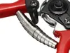 A close-up view of a red and silver garden shear, focusing on the spring mechanism. Podgląd zdjęcia produktu