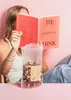 A person reading a book while holding a snack bag. Produktbild-Vorschau