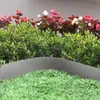A garden bed with green grass, green bushes, and colorful flowers. Produktbild-Vorschau