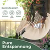 A person relaxing in a beige hammock chair on a balcony with plants and a railing. Produktbild-Vorschau
