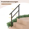 A black metal handrail is shown installed on a set of wooden stairs, with green foliage in the background. Voir les images du produit