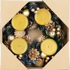 A Christmas advent wreath with four yellow candles, decorated with pine cones, gold baubles, and dark blue fabric flowers, presented in a cardboard box. Anteprima dell’immagine prodotto