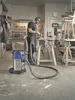 A man is working in a workshop with a vacuum cleaner. Anteprima dell’immagine prodotto