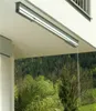 A retractable clothes drying rack mounted on the underside of a balcony or overhang, with a forest and trees visible in the background. Anteprima dell’immagine prodotto