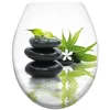 A stack of black stones with green bamboo leaves and a white flower, reflected in water. Produktbild-Vorschau