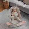 A baby is sitting in a baby bouncer on a rug in a living room. Produktbild-Vorschau