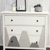 A dresser with mountain-themed drawers in a room with a wooden wall. Podgląd zdjęcia produktu
