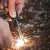 Hands using a fire starter to create sparks on the ground. Produktbild-Vorschau