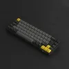 A mechanical keyboard with black, gray, and yellow keys is shown from a diagonal angle against a black background. Produktbild-Vorschau