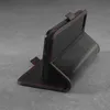 A black leather wallet case for a smartphone, with red stitching, is shown standing upright on a gray surface. Produktbild-Vorschau