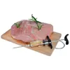 A raw piece of meat with rosemary sprigs inserted, placed on a wooden cutting board next to a marinade injector syringe filled with liquid. Náhled obrázku produktu
