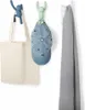 Three decorative hooks are mounted on a white wall, each holding a different item: a tote bag, a baseball cap, and a scarf. Náhled obrázku produktu