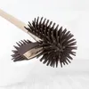A toilet brush with brown silicone bristles and a beige handle is shown in a bathroom setting, resting against a white toilet bowl. Anteprima dell’immagine prodotto