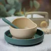 A close-up shot of a baby's silicone bowl and plate set with a spoon, with a toy vehicle in the background. Náhľad obrázku produktu