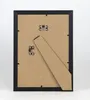 The back of a black picture frame with a brown backing board and a stand attached. Produktbild-Vorschau