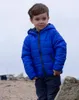 A young boy stands outdoors on a rocky, beach-like terrain. Produktbild-Vorschau