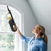A woman is cleaning a window with a handheld vacuum cleaner. Produktbild-Vorschau