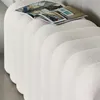 A close-up view of a white, textured bench with a magazine placed on top. Anteprima dell’immagine prodotto