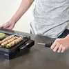 A person is using an electric grill to cook skewers of meat and vegetables. Podgląd zdjęcia produktu