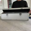 A person is holding open a silver aluminum case on a table. Produktbild-Vorschau