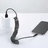 A coiled USB-C charging cable connected to a smartphone and a wall adapter. Anteprima dell’immagine prodotto