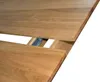 A close-up view of an extendable wooden dining table, showing the mechanism for adding extension leaves. Produktbild-Vorschau