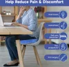 A woman sits at a desk using a laptop, with a blue seat cushion on her chair. Produktbild-Vorschau