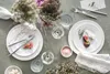 A table setting with plates, cutlery, glasses, and flowers. Produktbild-Vorschau