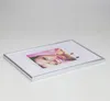 A silver photo frame with a picture of a woman's face and macarons inside, lying on a white surface. Produktbild-Vorschau