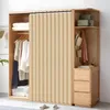 A closet with a beige pleated curtain divider, clothes hanging on hangers, and storage drawers. Produktbild-Vorschau
