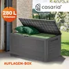 An outdoor storage box with cushions inside, placed on a patio with a garden in the background. Produktbild-Vorschau