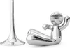 A silver bottle opener shaped like a person in a yoga pose and a separate silver stand are shown against a white background. Náhľad obrázku produktu