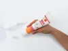 A hand holding a tube of Alpinaweiß SOS Innenfarbe, with some smudges on a white surface. Produktbild-Vorschau