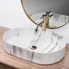 A marble sink with a gold faucet on a wooden surface, with a mirror in the background. Náhľad obrázku produktu