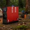 A red diesel heater is set up outdoors in a forest campsite setting, with a tent and camping gear visible in the background. Produktbild-Vorschau