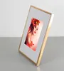 A gold picture frame with a photo of a woman adorned with autumn leaves. Produktbild-Vorschau