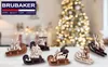 A collection of wooden Christmas sled ornaments displayed on a table in front of a blurred Christmas tree. Náhľad obrázku produktu