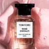A bottle of Tom Ford Rose D'Amalfi Eau de Parfum is presented against a soft pink, textured background with water droplets. Voir les images du produit